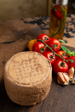 A small head of cheese. On a wooden table.