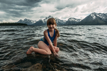 Young girl sitting on a rock in a mountain lake