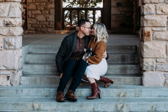 Young couple snuggling on steps with puppy