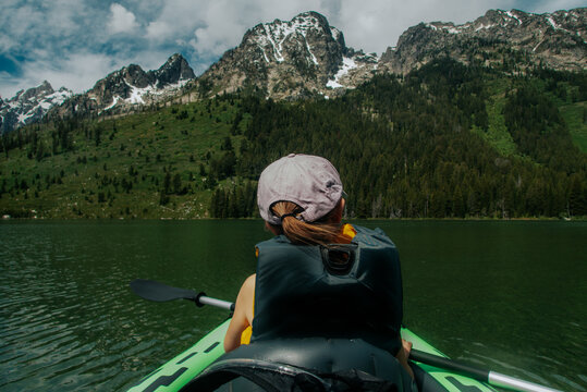 Back of young girl Kayaking in an alpine lake
