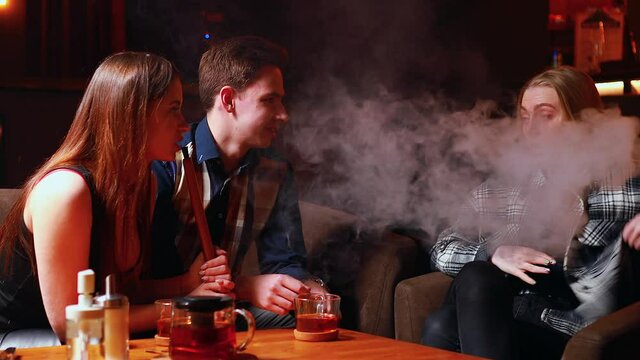 Authentic people Friends party in hookah lounge smoking shisha night time