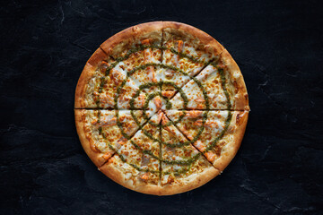 Pizza with salmon and cheese on a black stone background. Top view