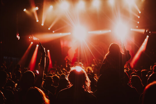 People at a rock concert dancing to the live band and music, with bright lights