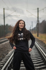 Obraz premium Portrait of a young beautiful dark-haired girl on the railroad tracks.