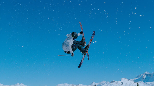 Expert freestyle skier rides up a kicker and does a breathtaking spinning trick.