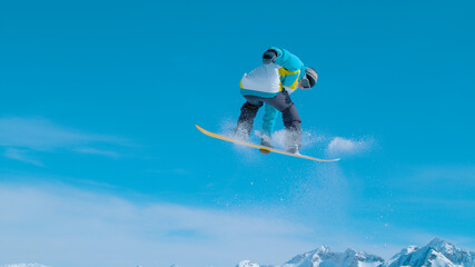 Fit male snowboarder doing a rotating grab while riding in Vogel ski resort - obrazy, fototapety, plakaty