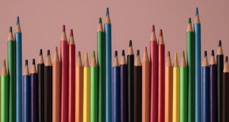 Many colored pencils in vertical on pink background