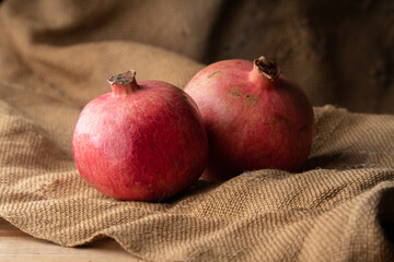 Two ripe juicy pomegranates on gray burlap. Food background.