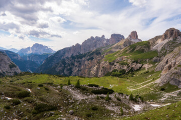 Fototapeta premium Trekking on a summer day in the tre cime valley, Dolomite italy. Alpine road, sunny day, clouds sky, trail, mountain