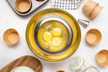 raw eggs for dough for cakes and molds for maffines on grey background.