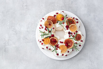 Meringues pavlova cake wreath with whipped cream, pomegranate and orange	