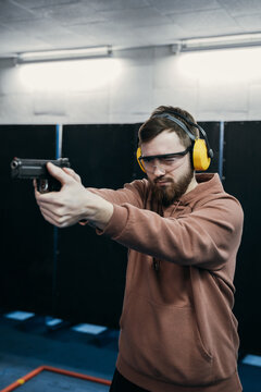 A man takes aim at a target before firing a pistol.