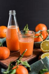 Frisch gepresster Orangensaft im Glas mit Citrusfrüchten auf dunklem Hintergrund. Fruchtiges Stillleben auf schwarzen Hintergrund mit frischen Früchten