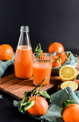 Frisch gepresster Orangensaft im Glas mit Citrusfrüchten auf dunklem Hintergrund. Fruchtiges Stillleben auf schwarzen Hintergrund mit frischen Früchten