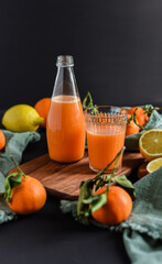 Frisch gepresster Orangensaft im Glas mit Citrusfrüchten auf dunklem Hintergrund. Fruchtiges Stillleben auf schwarzen Hintergrund mit frischen Früchten