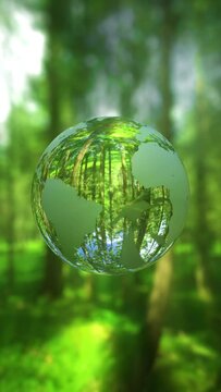3D animation - Looped rotating crystal ball shaped planet Earth in a green forest in vertical composition