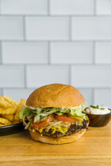 homemade burger cheddar bacon lettuce and tomato french fries gray background on wood