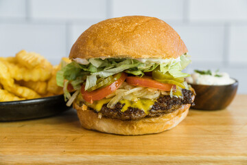 homemade burger cheddar bacon lettuce and tomato french fries gray background on wood
