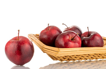 Several organic sweet, red apples on a straw platter, close-up, isolated on white.