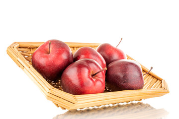 Several organic sweet, red apples on a straw platter, close-up, isolated on white.