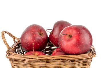 Several organic sweet red apples with a basket of vine, close-up, isolated on white.