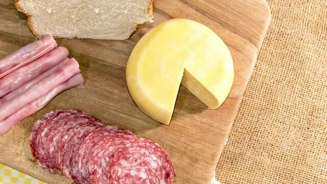 Slide show Colonial breakfast served with bread, cheese, ham and salami Top view.