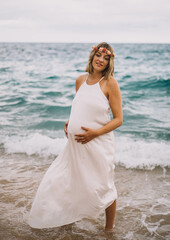 Fototapeta na wymiar Sesion de fotos de una mujer embarazada paseando por la playa