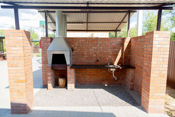Outdoor fireplace for barbecue with table and sink for cooking under the metal roof