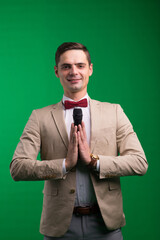 Portrait of a male announcer holding microphone, isolated on green, white background