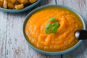 Bowl of pumpkin soup with cheese croutons and parsley