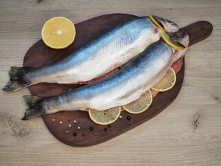 Raw pink char fish, salmon family, stuffed with lemon, spices and herbs on the kitchen board, top view. Recipe for healthy seafood Salvelinus alpinus for proper nutrition