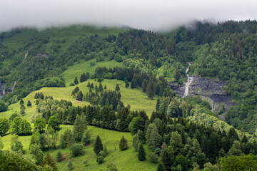 Obraz premium Panoramic view on mountain waterfalls, green forests and apline meadows near Saint-Gervais-les-Bains, Savoy. France