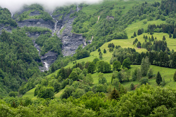Obraz premium Panoramic view on mountain waterfalls, green forests and apline meadows near Saint-Gervais-les-Bains, Savoy. France