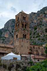 Fototapeta premium View on mountains cliff, old houses, green valley in remote medieval village Moustiers-Sainte-Marie in Provence, France