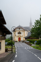 Fototapeta na wymiar View on mountain chapel in foggy small village near Saint-Gervais-les-Bains, Savoy, France