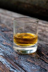 Glass of strong scotch single malt whisky on old log soaked in creosote