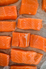 Top view of fresh raw salmon fillet pieces on parchment