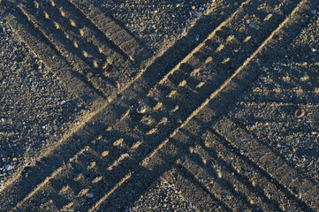 traces of truck tires in the sand that intersect perfectly in the shape of the letter x