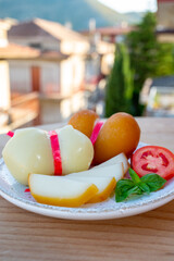 Cheese collection, variety of Italian cow milk cheese scamorza with Italian houses on background