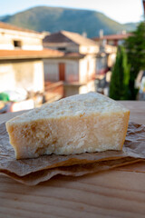 Cheese collection, piece of matured cow cheese pasmesan parmigiano reggiano and Italian houses on background