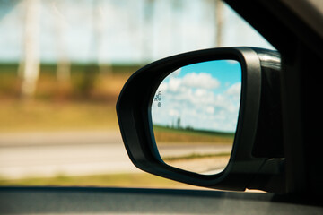 A blind spot monitoring sensor on the side mirror of a modern car
