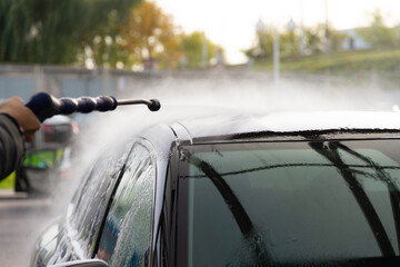 Washing a black car in the fresh air. Rinse the car with water