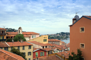 Colorful houses in Villefranche-sur-Mer against the sky of the French Riviera. Roofs of bright yellow houses. Travel along the Cote d'Azur.