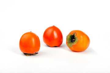 Three ripe persimmon fruits on a white background.