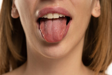 Cropped image of young woman showing tongue