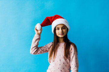 Portrait of a young girl wearing Santa's hat isolated on blue background