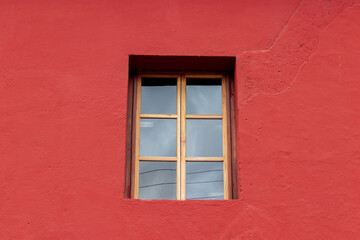 colonial window  on a red wall in antigua guatemala