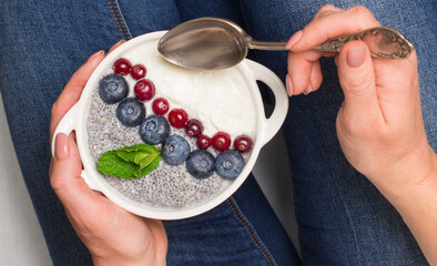 Healthy breakfast. Chia seeds and yoghurt with berries in woman hands.