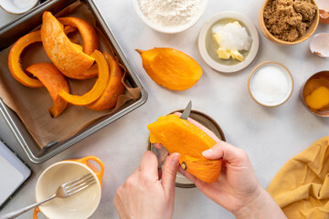Process of peeling, cutting orange pumpkin by female hands. Cooking pumpkin cake or muffins. Top view. Step by step process.