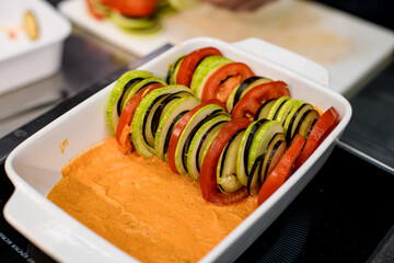 plate with sliced different vegetables arranged in a row and covered with sauce